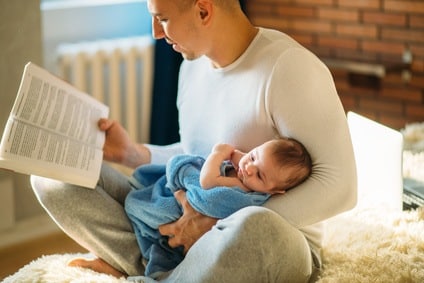 Young father and reading book to little baby